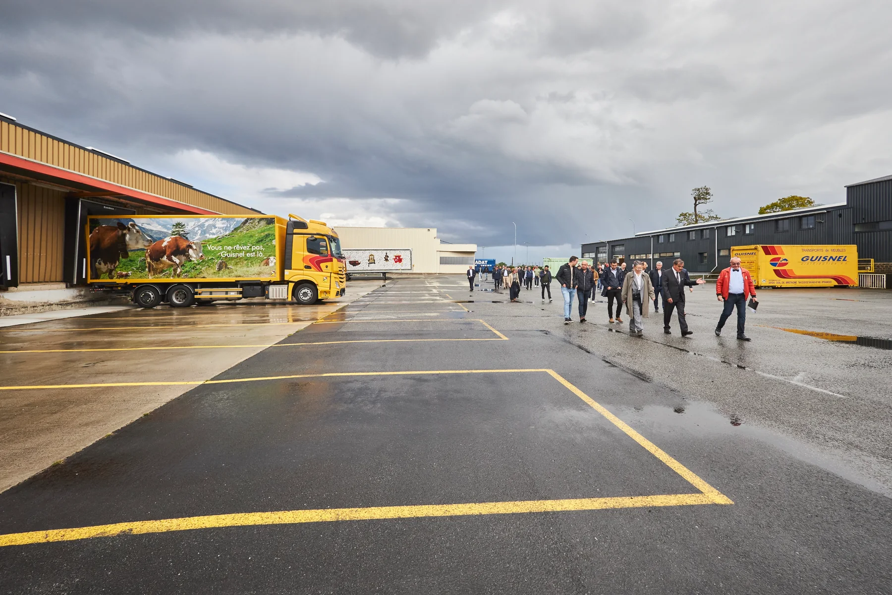 Arrivée des invités sur le site du groupe Guisnel à Dol-de-Bretagne, camions et ciel d'orage