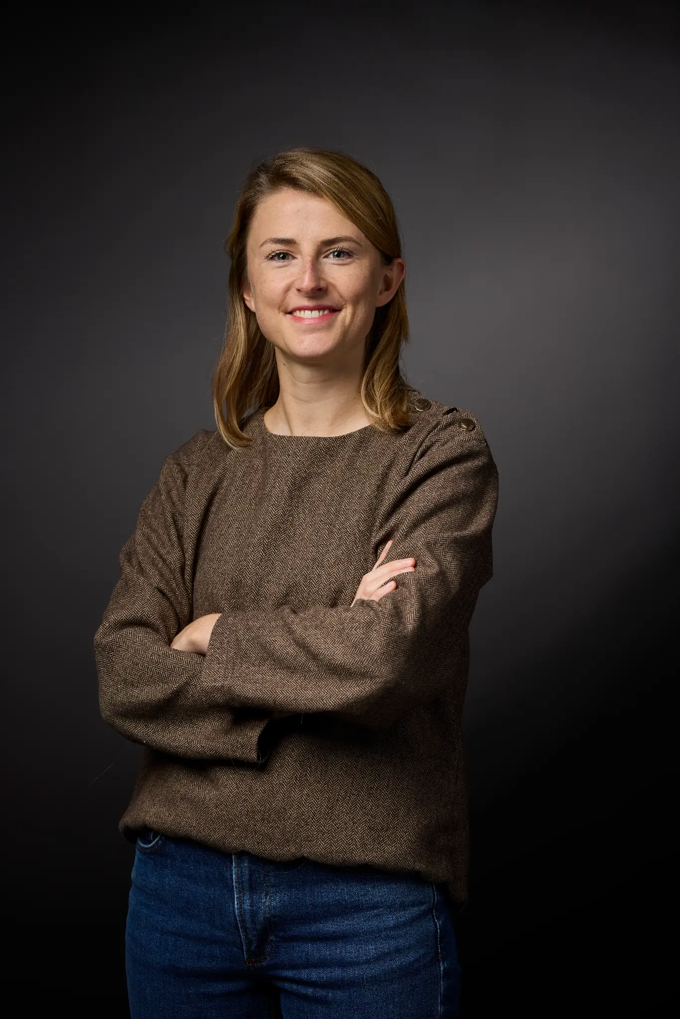 Portrait corporate femme pull marron bras croisés sourire naturel fond gris — Photographe portrait professionnel LinkedIn Dol-de-Bretagne, Saint-Malo, Ille-et-Vilaine