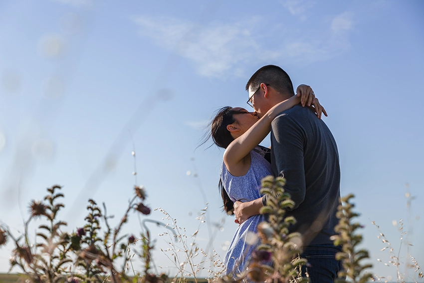 Couple kissing in the meadows of Mont Saint-Michel in backlight — engagement couple photography Normandy